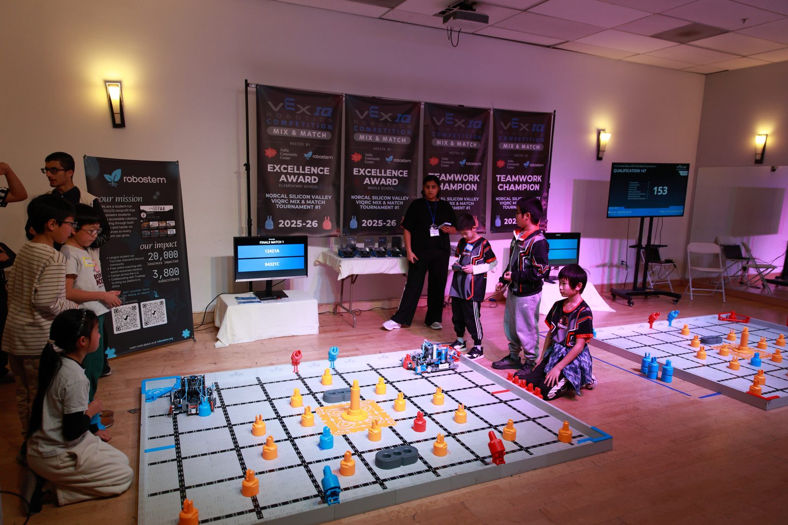 Two VEX IQ Mix & Match fields in the ICC hall, with award banners and the RoboSTEM booth behind