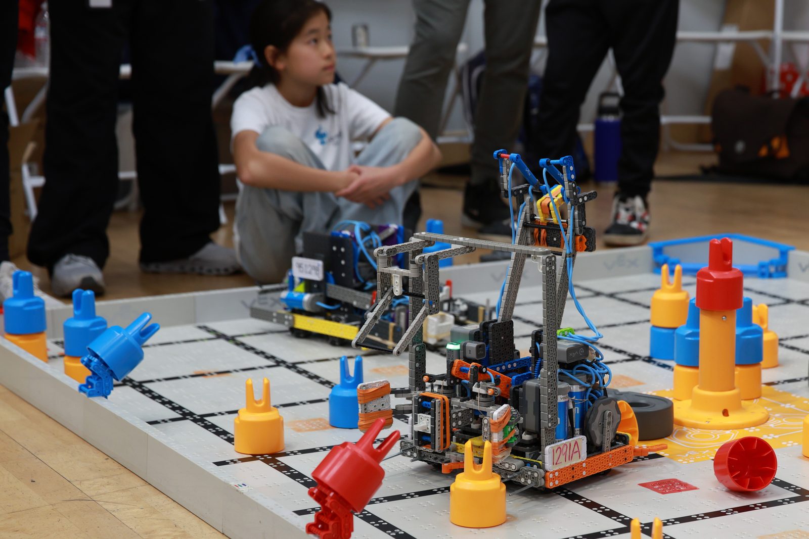 Two VEX IQ robots mid-match among the orange and blue game pieces